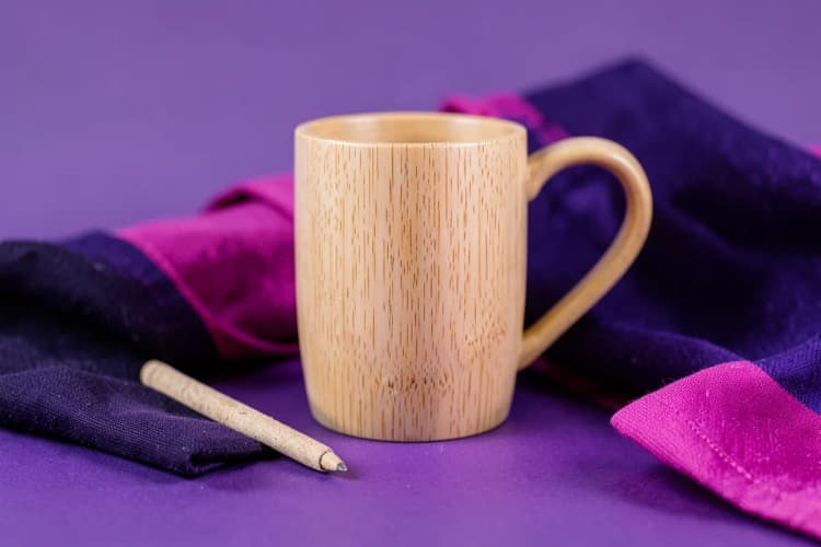 Conjunto de brindes sustentáveis: uma caneca de bambu, uma caneta de papel reciclado e uma sacola de algodão orgânico.